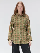 Camisa de seda con estampado geométrico de cuadrados en tonos rojizos y marrones. Presenta cuello camisero, cierre frontal con botones, bolsillo en el pecho y mangas largas con puños abotonados.