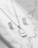 Set de joyería compuesto por un collar con dije rectangular y un par de aros a juego, ambos con incrustaciones de nácar y estructura de acero inoxidable.