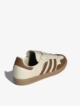 Championes Adidas modelo Samba OG, con exterior de cuero premium en color crema y detalles en marrón, suela de caucho y diseño clásico de inspiración futbolística.