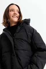 Campera puffer corta de color negro, con capucha, cierre frontal con cremallera y solapa con botones a presión.