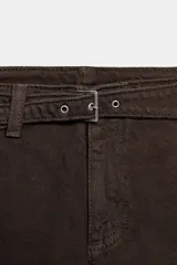 Short de tiro bajo en denim color marrón, con diseño de corte estructurado y detalle de cinturón integrado con hebilla metálica.