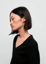 Jersey de punto fino color negro, con cuello en V y solapa tipo polo, de corte recto y manga larga.