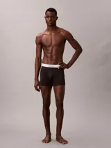 Pack de tres bóxers Calvin Klein tipo boxer brief de algodón elástico. Incluye un modelo negro con monograma estampado, uno azul oscuro liso y uno gris claro liso. Todos cuentan con cintura elástica blanca con el logo de la marca.