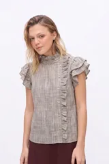 Blusa sin mangas de color beige oscuro con patrón a cuadros, cuello alto con volados, cierre lateral asimétrico con botones y detalles de volados en los hombros y la botonera.