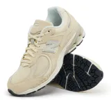 Championes urbanos New Balance modelo 2002R, color beige, confeccionados en una combinación de gamuza y malla transpirable. Presentan el logo N característico en los laterales, entresuela con tecnología N-ergy para mayor amortiguación y suela de goma resistente.