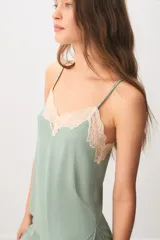 Pijama de dos piezas color verde menta, confeccionado en poliamida y elastano. Incluye una musculosa con tirantes finos y detalles de encaje beige en el escote, y un short con cintura elástica, pequeño lazo decorativo y apliques de encaje en los ruedos.