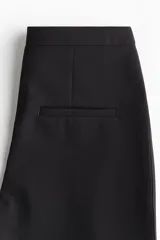 Pantalón de tiro alto con corte acampanado, cierre frontal oculto y bolsillos traseros insertados.