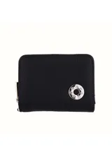 Monedero negro de cuero sintético con cierre de cremallera y aplique metálico circular plateado con logo de la marca.
