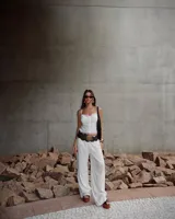 Cinturón ancho de cuero negro con diseño de círculos superpuestos. Presenta apliques metálicos circulares en tono dorado envejecido, algunos lisos y otros con grabado tribal/étnico. Los círculos de cuero tienen ojales metálicos pequeños alrededor de los apliques grandes.