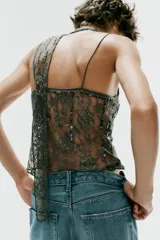 Top de encaje color gris oscuro, con escote en pico, tirantes finos y detalle de pañuelo incorporado al cuello. Presenta aplicaciones de abalorios y lentejuelas a contraste.