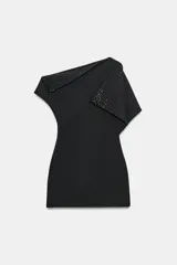 Vestido mini negro de escote y mangas asimétricas con pliegues y aplicaciones de brillos.