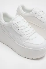 Zapatillas blancas tipo bamba con plataforma de 7 cm, cierre con cordones y punta redonda.