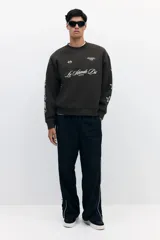Buzo verde militar de corte oversized, confeccionado en mezcla de algodón con cuello redondo, puños y dobladillo acanalados. Cuenta con estampados en el frente, la espalda y las mangas, incluyendo inscripciones y estrellas.