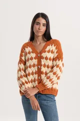 Cardigan de punto con diseño geométrico en contraste, escote en V y cierre frontal con botones. Presenta un calce relajado y mangas largas.