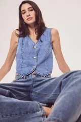 Chaleco de denim celeste con cuello en V y cierre frontal con botones metálicos.