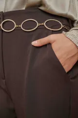 Cinturón de cadena en tono dorado, compuesto por eslabones en forma de óvalo decorados con strass brillante.