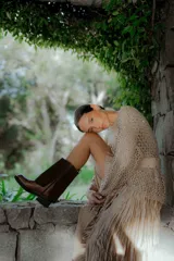 Buzo de tejido abierto con acabado brillante, cuello redondo y mangas largas. Presenta un diseño de punto calado con sutiles lentejuelas incorporadas en el tejido.