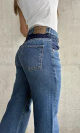 Pantalón de jean de tiro alto, color azul con detalles en azul oscuro en los bolsillos delanteros.