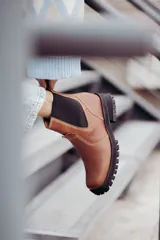 Bota tipo chelsea de cuero color marrón oscuro, con paneles laterales elásticos y suela track robusta con plataforma.