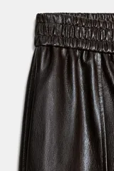 Bermuda de tiro alto confeccionada en material efecto piel, con cintura elástica y costuras verticales decorativas en el frente.