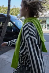 Camisa de cuello solapa con escote pico y manga larga. Presenta un bolsillo delantero de plastrón y bajo con aberturas laterales con cordones ajustables. Cierre frontal con botones.