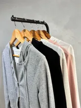 Campera negra de tejido fino con capucha, manga larga y cierre frontal metálico de doble cursor. Presenta un diseño entallado y minimalista.