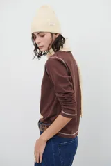 Remera de manga larga con cuello redondo, confeccionada en tejido de punto gris melange con costuras visibles en contraste.