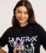 Remera negra de algodón con cuello redondo y manga corta. Presenta un estampado frontal con el texto "HUNTRAX" y tres personajes femeninos de estilo anime/k-pop.