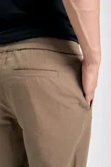 Pantalón casual color marrón claro, confeccionado en lino con suave elasticidad, corte recto y cintura con cordón ajustable.