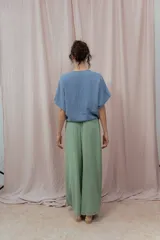 Blusa de lino color fucsia, con escote en V y manga corta amplia. Presenta un detalle de botón decorativo dorado en el centro del escote.