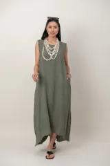 Vestido largo de lino color verde militar, sin mangas, con cuello redondo y bolsillos laterales. Presenta detalles desflecados en las sisas y en el dobladillo asimétrico.