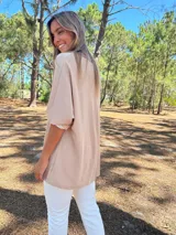 Buzo oversize color beige con cuello redondo, manga larga y corte asimétrico en el bajo.