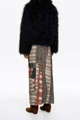 Chaqueta de pelo sintético negro con textura de pelo largo, cierre frontal con cremallera y cuello alto. Diseño de corte corto y envolvente.