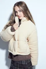 Campera puffer de corderito negro con cuello alto y diseño oversized. Presenta una textura tipo teddy, cierre frontal y corte a la cintura.