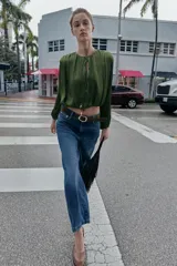 Jeans de tiro alto con pernera ancha y corte cropped. Presenta diseño de cinco bolsillos, cierre frontal con cremallera y botón, e incluye un cinturón a juego.