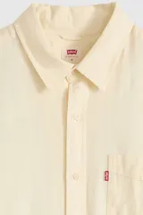 Camisa de manga larga color amarillo claro, con cuello camisero, cierre frontal de botones y un bolsillo aplicado en el pecho con etiqueta roja de la marca.