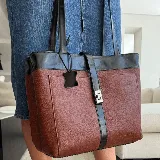 Bolso tipo tote de cuero color marrón con detalles en negro. Tiene doble asa de hombro y correa extraíble regulable. Incluye cierre principal y bolsillo interior.