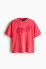 Remera boxy de algodón liviano en color coral, con efecto acid wash, hombros caídos, cuello redondo ribeteado y corte oversized. Cuenta con bordado en relieve con la palabra 'Sunset' en el frente.
