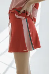 Minifalda de punto a rayas en tonos rojo, rosado y detalles en verde, con cintura elástica con cordón ajustable.