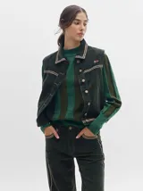 Chaleco de pana color negro con cuello camisero, cierre frontal con botones metálicos dorados, costuras contrastantes en tono claro y pequeño parche distintivo en el pecho.