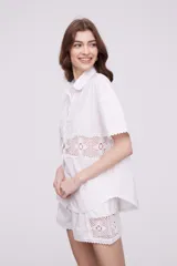 Camisa blanca de algodón con apliques de crochet calado en la cintura, manga corta y cuello camisa.