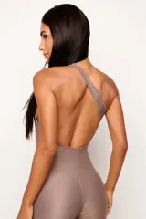 Jumpsuit deportivo de una sola pieza, con diseño asimétrico de un solo hombro y espalda descubierta. Confeccionado en tejido de poliamida con acabado mate, ofrece un ajuste ceñido y elástico ideal para actividades físicas o looks urbanos.