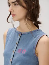 Musculosa MUTMA Trebola de silueta recta confeccionada en tejido de punto color gris con efecto lavado. Posee cierre frontal con botones, detalle de bordado en el pecho y terminación festoneada en el ruedo y las sisas.