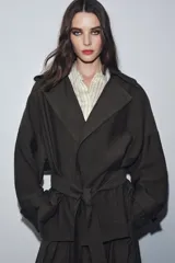 Chaqueta fluida de color verde oliva, con cuello solapa, manga larga ajustable con trabilla y botón, y cinturón del mismo tejido anudado a la cintura.