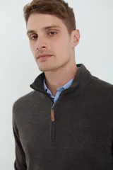 Sweater verde oliva de tejido acrílico con textura similar al cashmere, corte clásico, cuello alto con cierre metálico y tirador de cuerina ecológica.