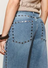 Jeans de denim celestes de tiro medio, diseño de corte recto y amplio con detalles de tachuelas en los bolsillos delanteros.