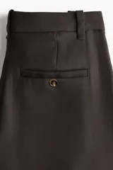 Pantalón sastrero de corte ancho, color negro, con cierre y botón frontal, pinzas en la cintura y raya marcada en las piernas.