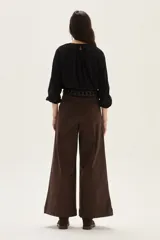 Blusa de algodón de corte holgado, con cuello redondo fruncido y cierre de lazo frontal. Presenta mangas largas con puños elásticos.