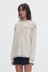 Remera de manga larga negra con bolsillo frontal en el pecho y costuras a la vista en contraste de color gris.