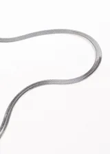 Cadena dorada de acero quirúrgico con eslabones planos tipo serpiente, cierre de mosquetón y cadena de extensión.